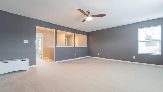 an empty room with windows and ceiling fan