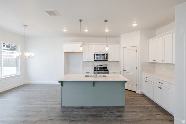 4741 Olive Avenue, Unit 406 Mapleton, UT 84664 - Photo 4 of 20 Two tone kitchen with a center island with sink, two tone color scheme, stainless steel appliances, a breakfast bar area, and a chandelier