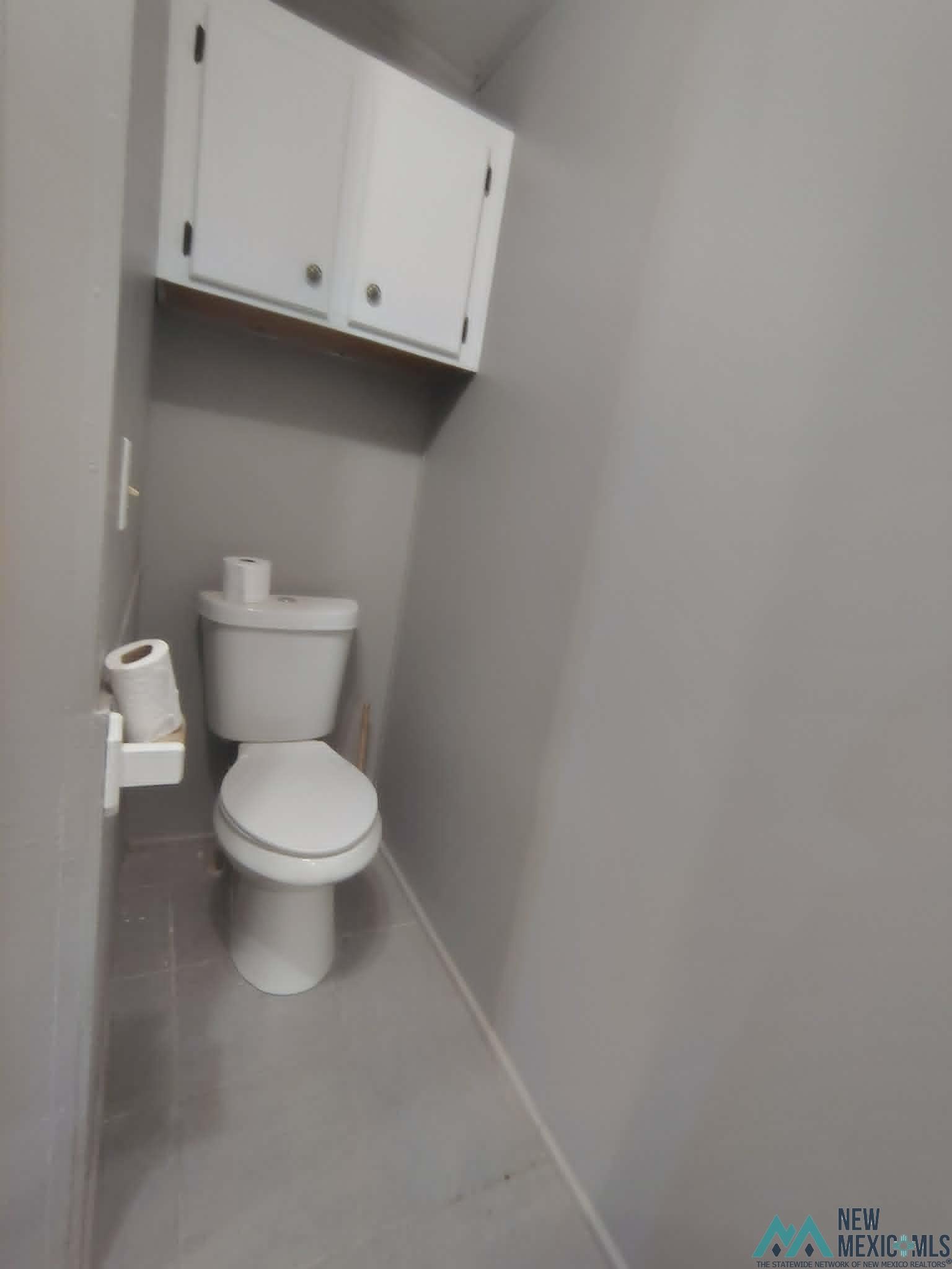 58 Fisk Road Dexter, NM 88230 - Photo 26 of 46 White toilet with an overhead storage cabinet featuring two doors and gold-toned hardware