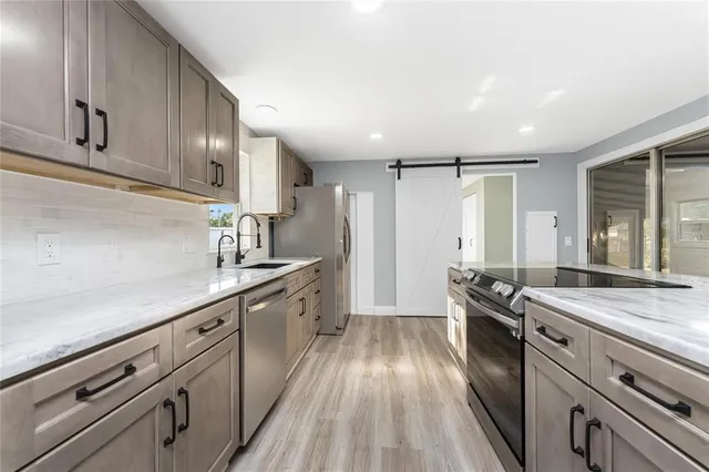 a kitchen with stainless steel appliances sink stove refrigerator and cabinets