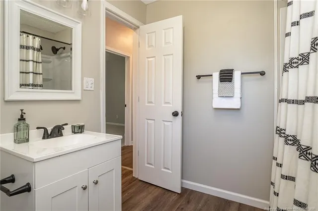 a dining room with wooden floor a chandelier fan a kitchen view and a chandelier