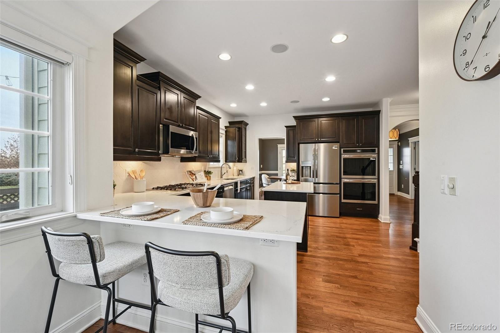 8741 East 33rd Avenue Denver, CO 80238 - Photo 13 of 43 a kitchen with stainless steel appliances kitchen island granite countertop a refrigerator a stove a microwave oven a sink with island and chairs
