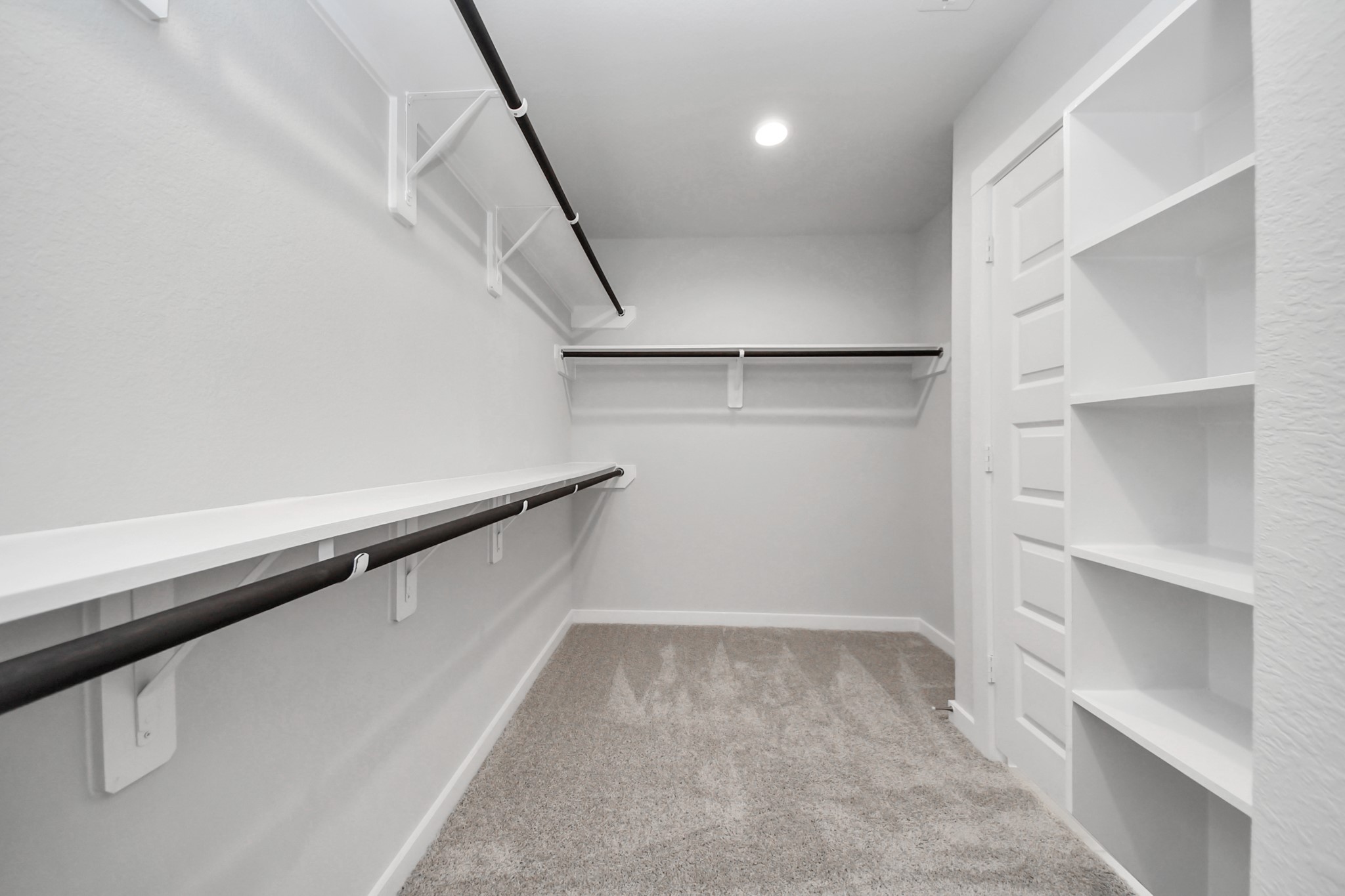 24518 Broad Park Spring, TX 77373 - Photo 27 of 29 Experience luxury in this spacious walk-in closet with high ceilings and plush carpet. Warm paint tones, built-in shelving, and dark finishes create a contemporary and functional retreat. Sample photo of completed home with similar floor plan. Actual colors and selections may vary.
