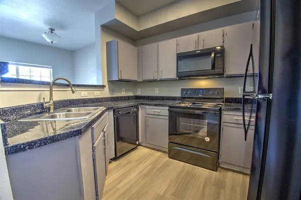 a kitchen with stainless steel appliances granite countertop a stove a sink and a microwave