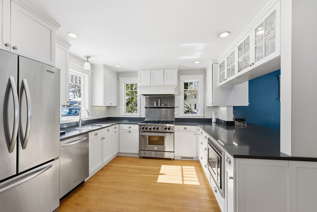 53 Prairie Street Concord, MA 01742 - Photo 3 of 26 a kitchen with stainless steel appliances granite countertop a stove top oven a refrigerator a sink and dishwasher with wooden floor