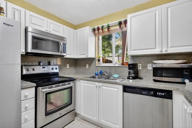 a kitchen with stainless steel appliances granite countertop a stove a microwave a sink and cabinets