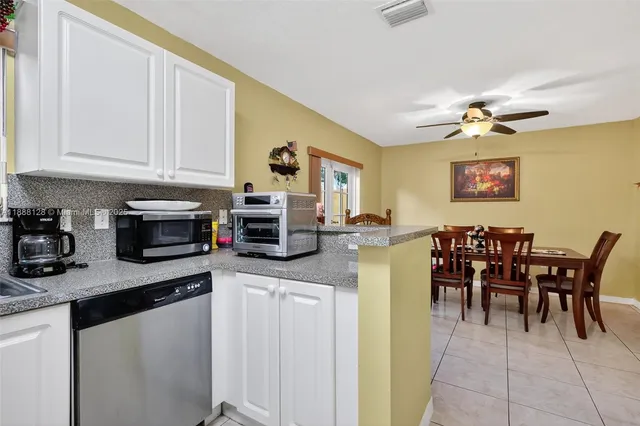 a kitchen with stainless steel appliances granite countertop a refrigerator a stove a sink a dining table and chairs with wooden floor