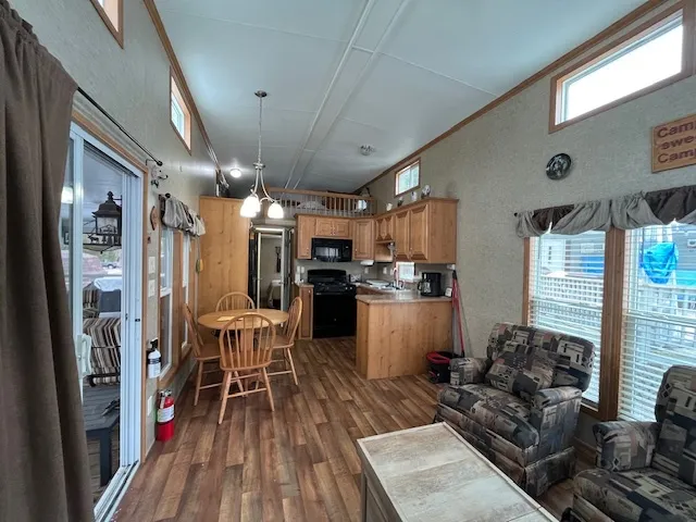 a kitchen with stainless steel appliances granite countertop a refrigerator a sink dishwasher a stove and a dining table with wooden floor