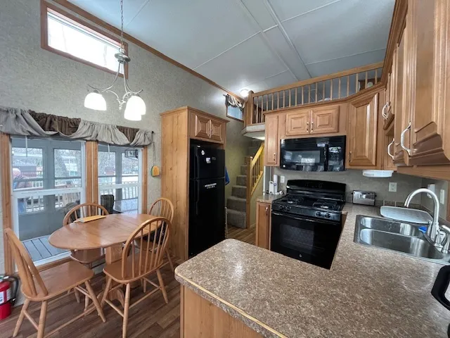 a kitchen with stainless steel appliances kitchen island granite countertop a refrigerator a stove a sink a dining table and chairs with wooden floor