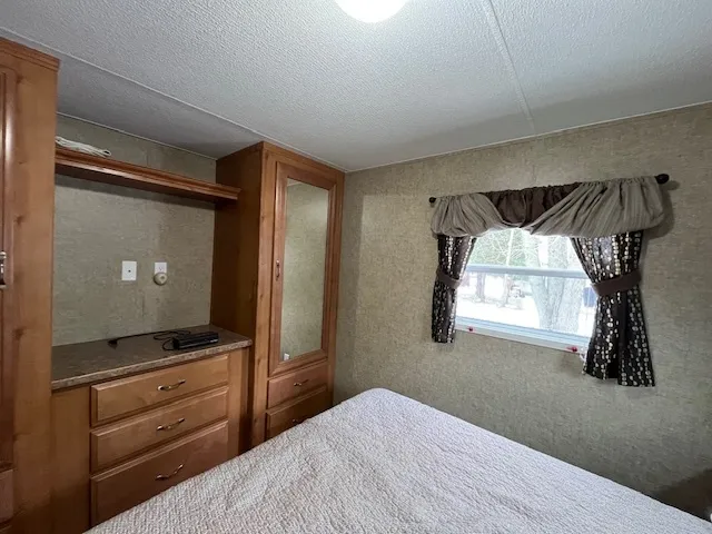 a bedroom with a bed and a flat tv screen on a dresser