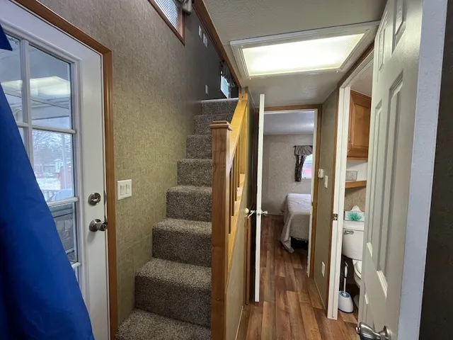 a view of a hallway with wooden floor and livingroom with furniture