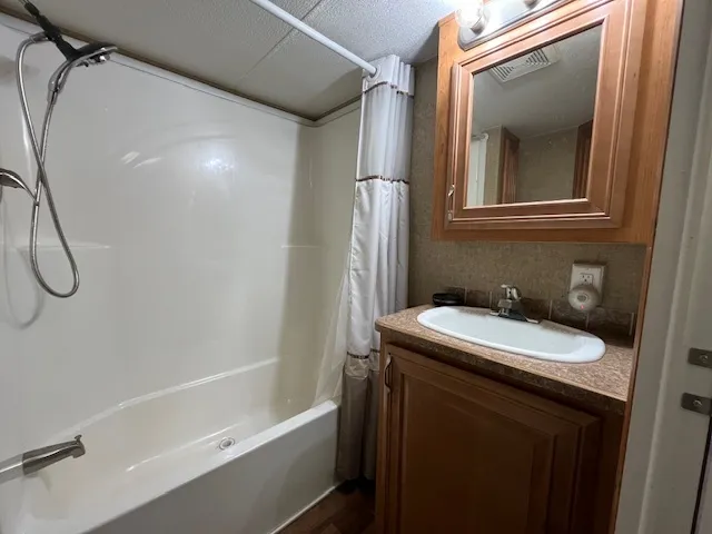 a bathroom with a granite countertop bathtub sink vanity mirror and toilet