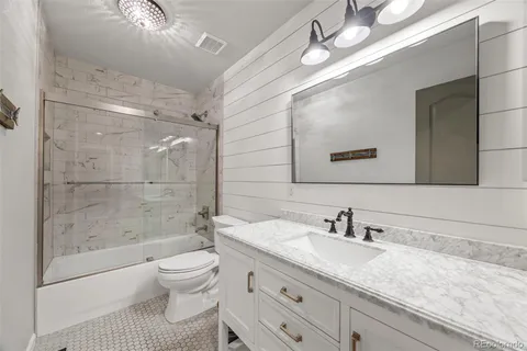 a bathroom with a granite countertop sink a toilet and shower