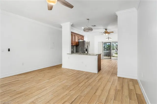a view of kitchen and empty room with wooden floor