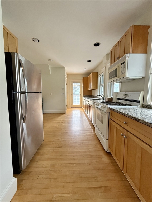 a kitchen with stainless steel appliances granite countertop a refrigerator a stove and a sink