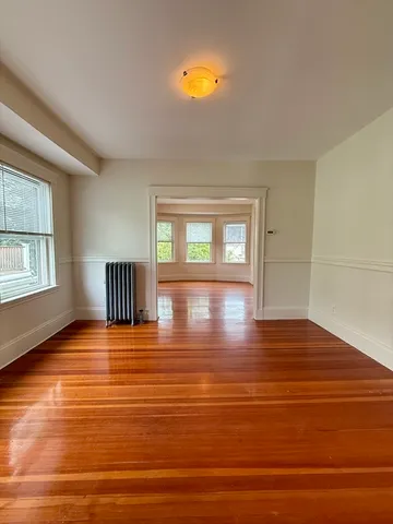 a view of an empty room with window and wooden floor