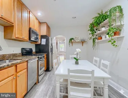 a kitchen with stainless steel appliances a sink a stove top oven a chimney and cabinets