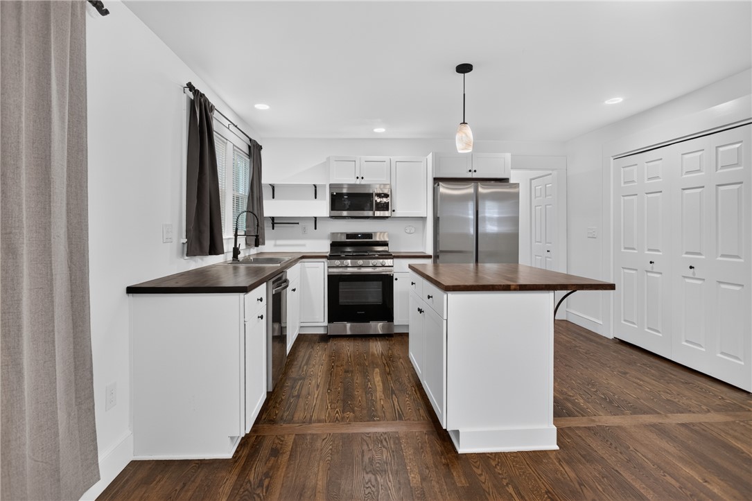 115 Pelfrey Street Seneca, SC 29672 - Photo 7 of 46 A well-appointed kitchen showcasing dark wood flooring, white cabinetry, and stainless steel appliances.