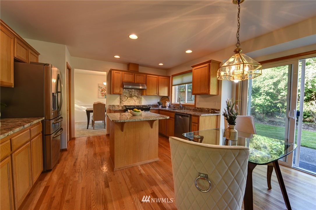 23215 9th Place West Bothell, WA 98021 - Photo 8 of 24 a kitchen with stainless steel appliances granite countertop a refrigerator a stove top oven and a dining table with wooden floor