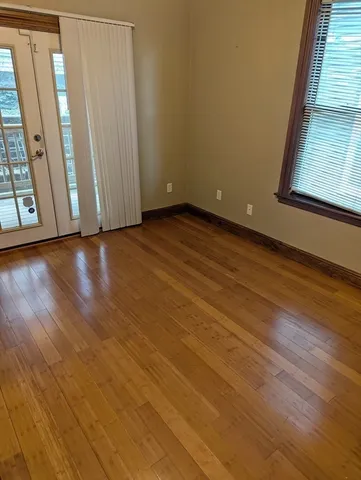 a view of an empty room with wooden floor and a window