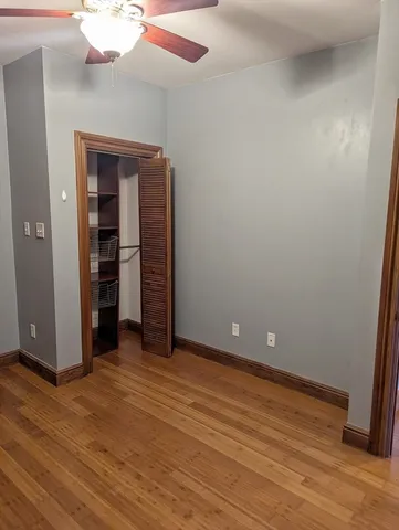 a view of an empty room with wooden floor and closet
