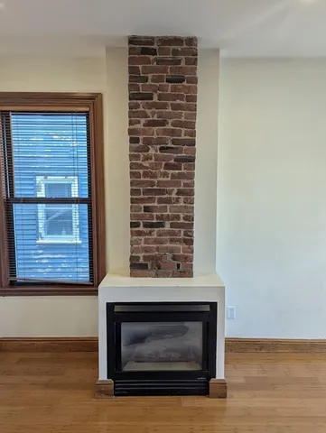 a view of empty room with wooden floor and a fireplace