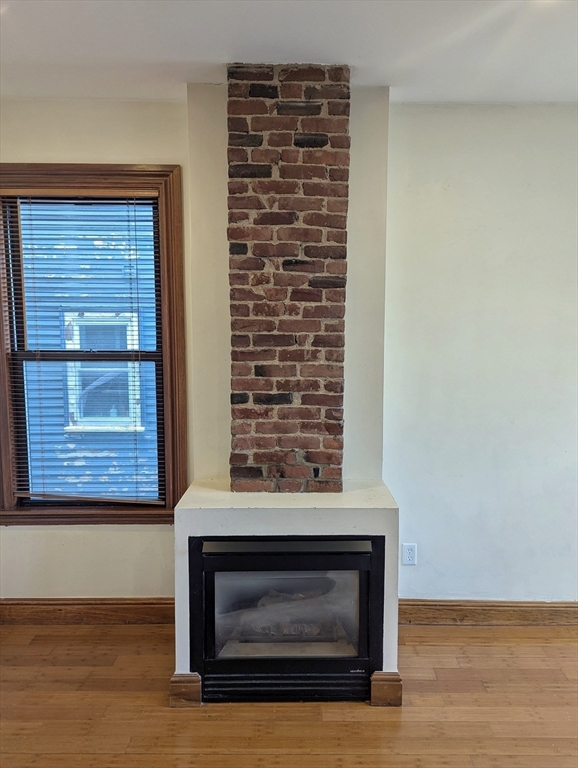 176 Hillside Street, Unit 101 Boston, MA 02120 - Photo 3 of 16 a view of empty room with wooden floor and a fireplace