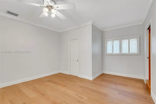 a view of an empty room with wooden floor and a ceiling fan