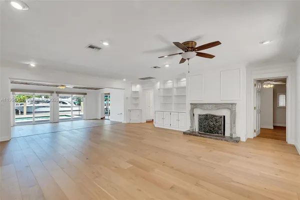 an empty room with fireplace chandelier fan and windows