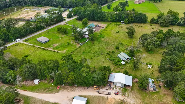 an aerial view of a residential houses with outdoor space and trees all around