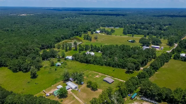 an aerial view of a residential houses with outdoor space and trees all around