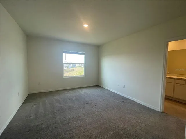 a view of an empty room with a window and a kitchen