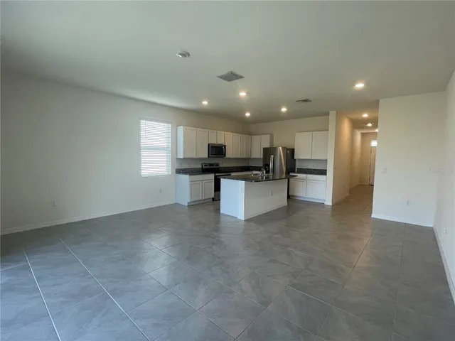 a view of kitchen with kitchen island stainless steel appliances refrigerator sink and cabinets