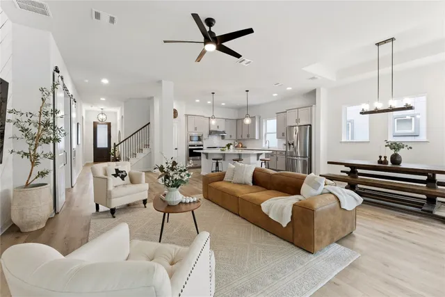 a living room with furniture kitchen view and a chandelier