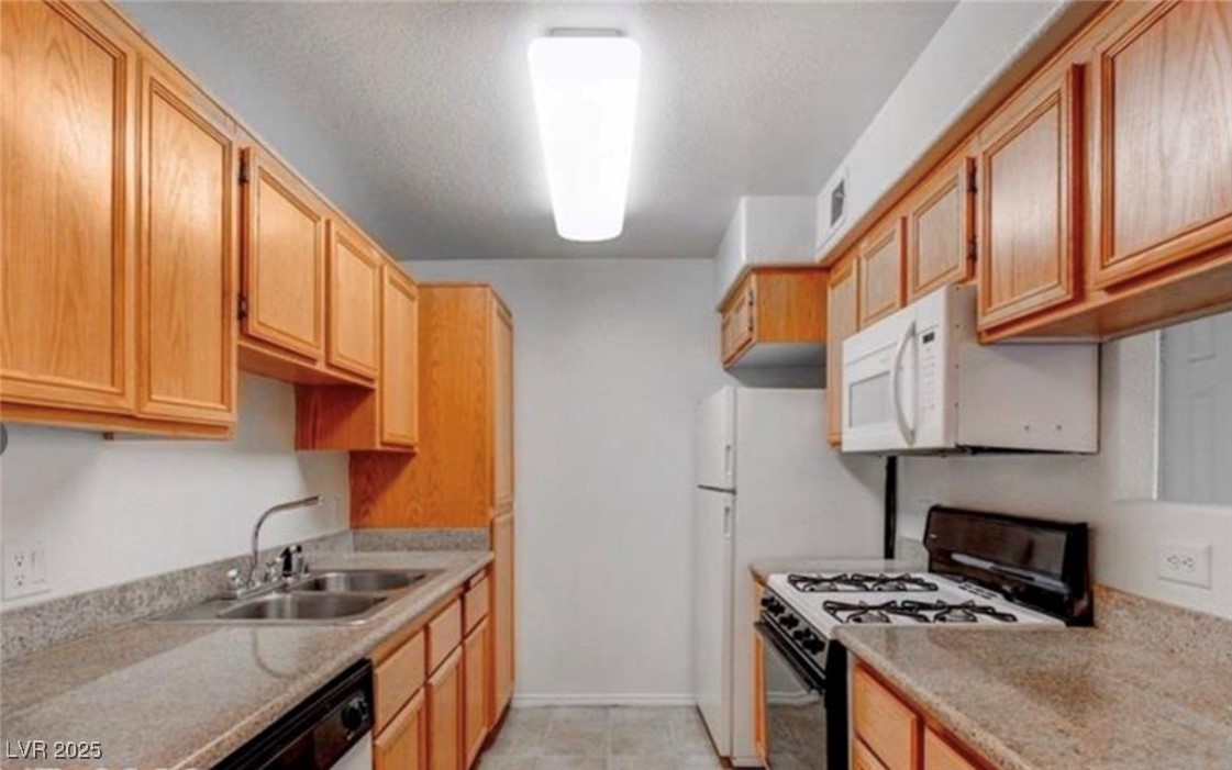 Kitchen featuring gas stove, white microwave, light countertops, dishwashing machine, and a textured ceiling