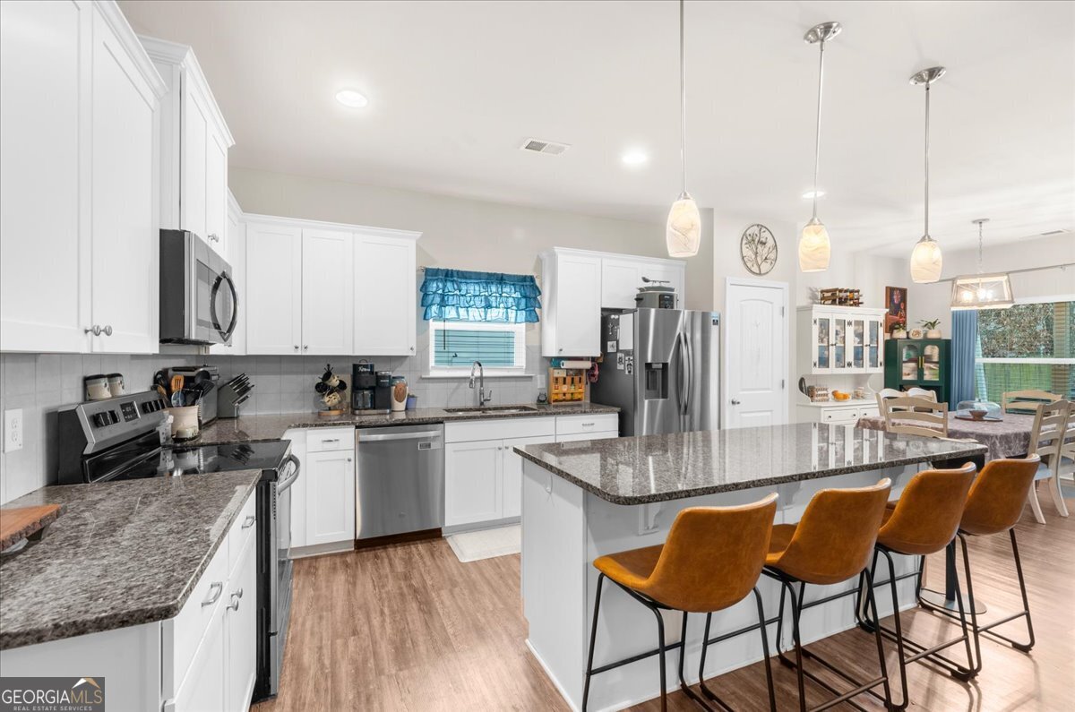 15 Gala Drive Northeast Rome, GA 30165 - Photo 22 of 60 a kitchen with stainless steel appliances granite countertop a stove top oven a sink a dining table and chairs with wooden floor