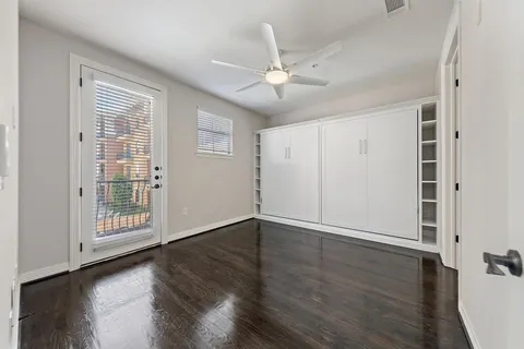 an empty room with wooden floor fan and windows