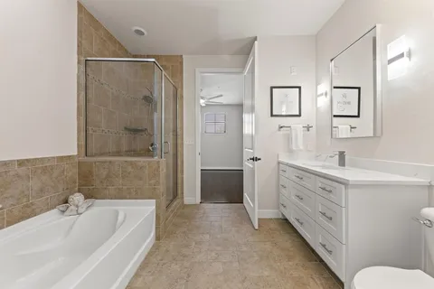 a bathroom with a double vanity sink a toilet a shower and a bathtub
