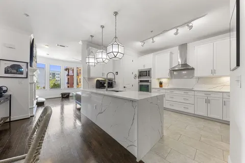 a large kitchen with kitchen island white cabinets and stainless steel appliances