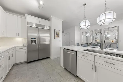 a kitchen with stainless steel appliances granite countertop a sink a refrigerator and a white cabinets