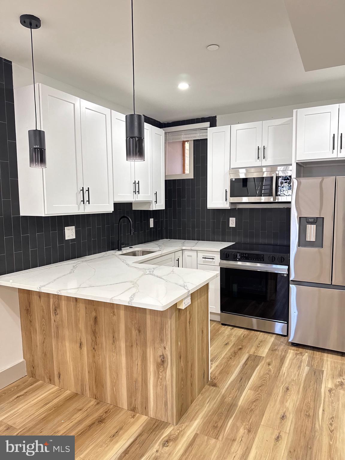 2031 North 19th Street, Unit A Philadelphia, PA 19121 - Photo 4 of 17 a kitchen with stainless steel appliances a stove a sink and white cabinets