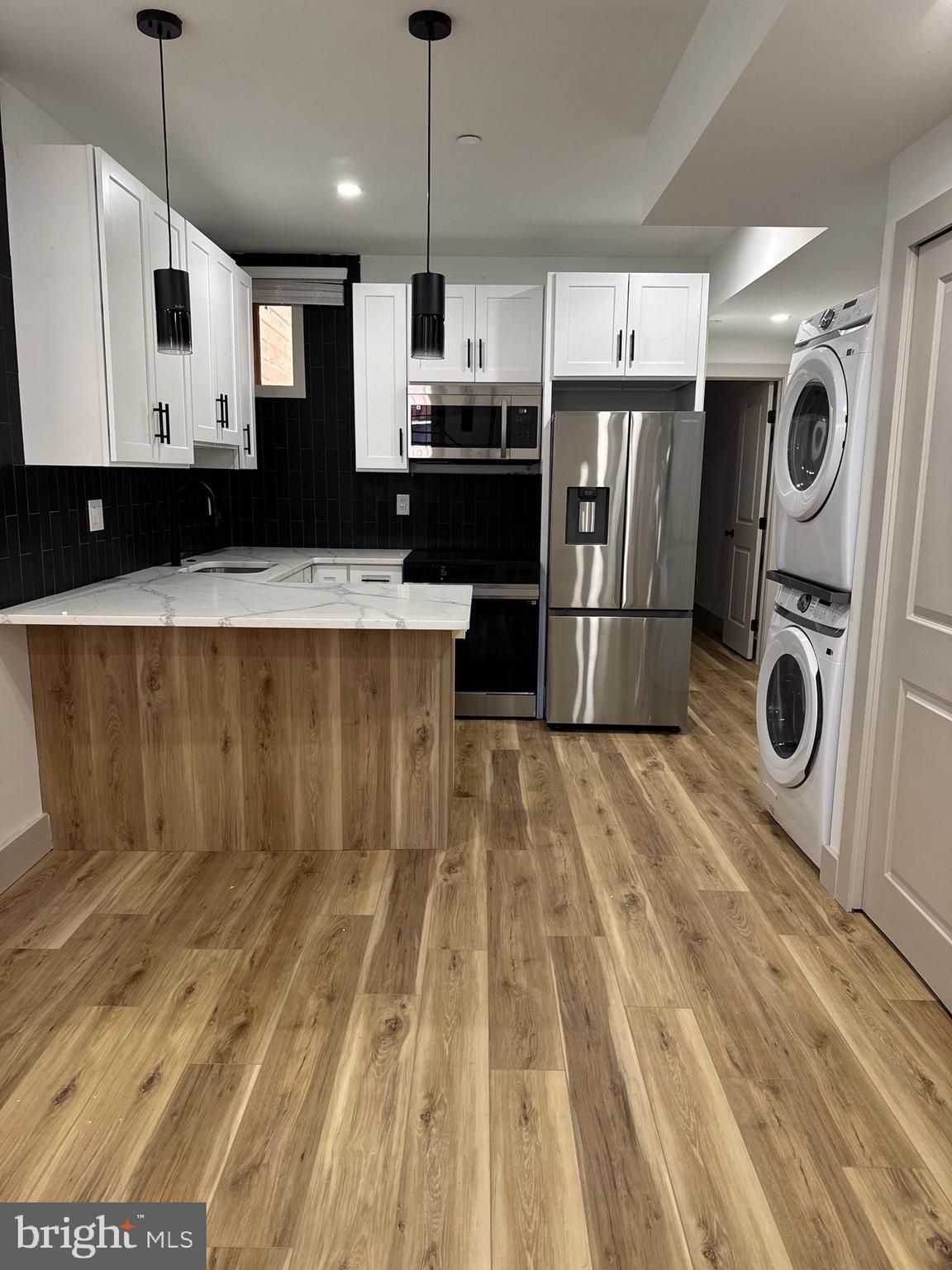 2031 North 19th Street, Unit A Philadelphia, PA 19121 - Photo 5 of 17 a kitchen with kitchen island a stove a microwave and a refrigerator