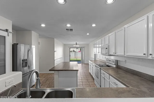 a kitchen with granite countertop a sink a stove and refrigerator