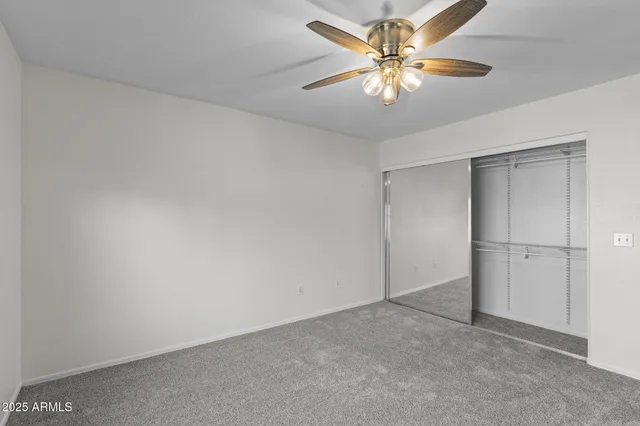 an empty room with a chandelier fan and windows