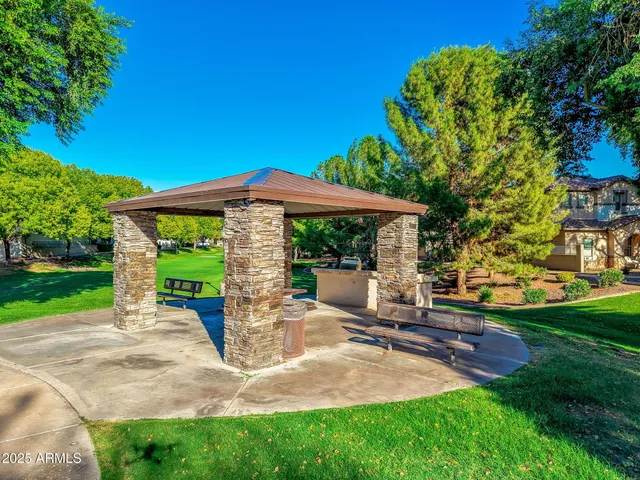 a view of a patio with table and chairs under an umbrella with large trees