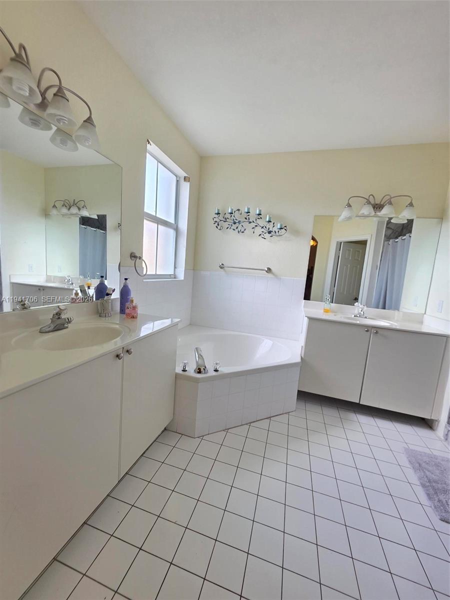 11702 Southwest 137th Place Miami, FL 33186 - Photo 19 of 30 a bathroom with a bathtub sink vanity and mirror