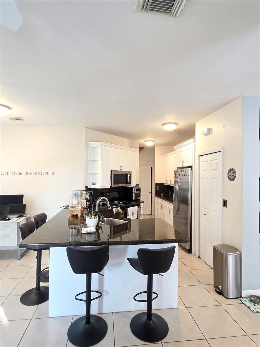 11702 Southwest 137th Place Miami, FL 33186 - Photo 7 of 30 a kitchen with stainless steel appliances kitchen island granite countertop a table and chairs