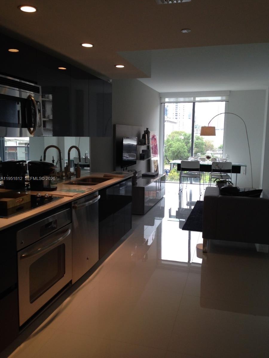 31 Southeast 6th Street, Unit 603 Miami, FL 33131 - Photo 3 of 3 a kitchen with stainless steel appliances kitchen island granite countertop a sink dishwasher stove and cabinets