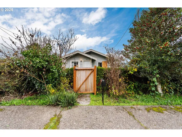 a view of a wooden house with a yard and large trees