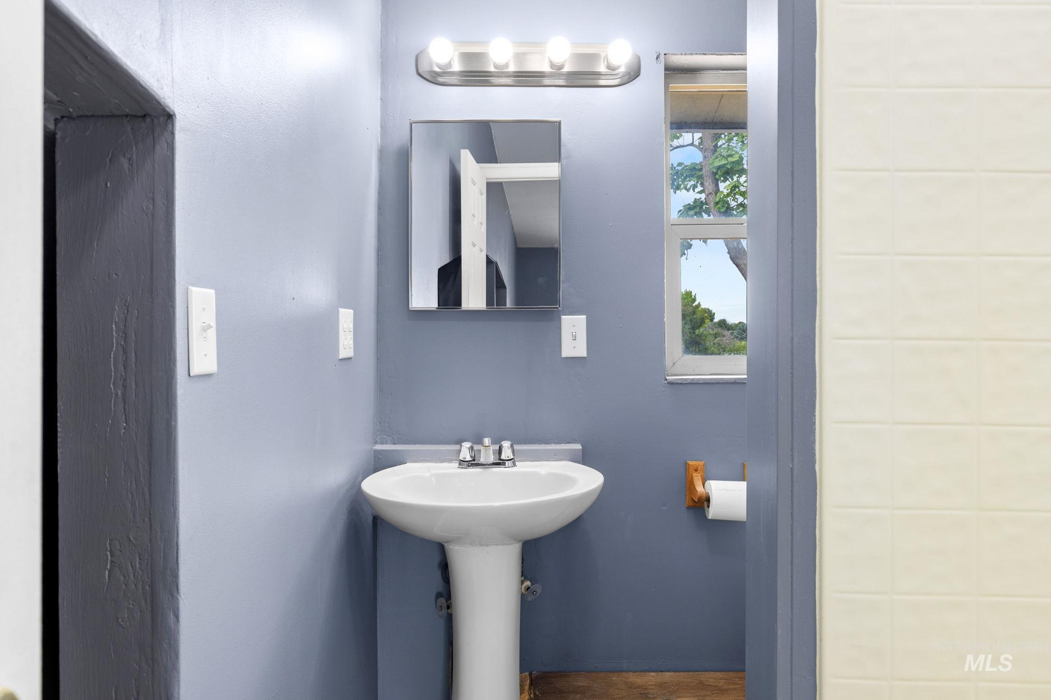 18338 Pride Lane Caldwell, ID 83607 - Photo 39 of 50 Pedestal sink with chrome faucet, illuminated by a four-bulb vanity light fixture